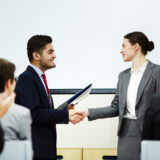 Shaking hand of speaker Coach congratulating one of business course attendants on graduation event