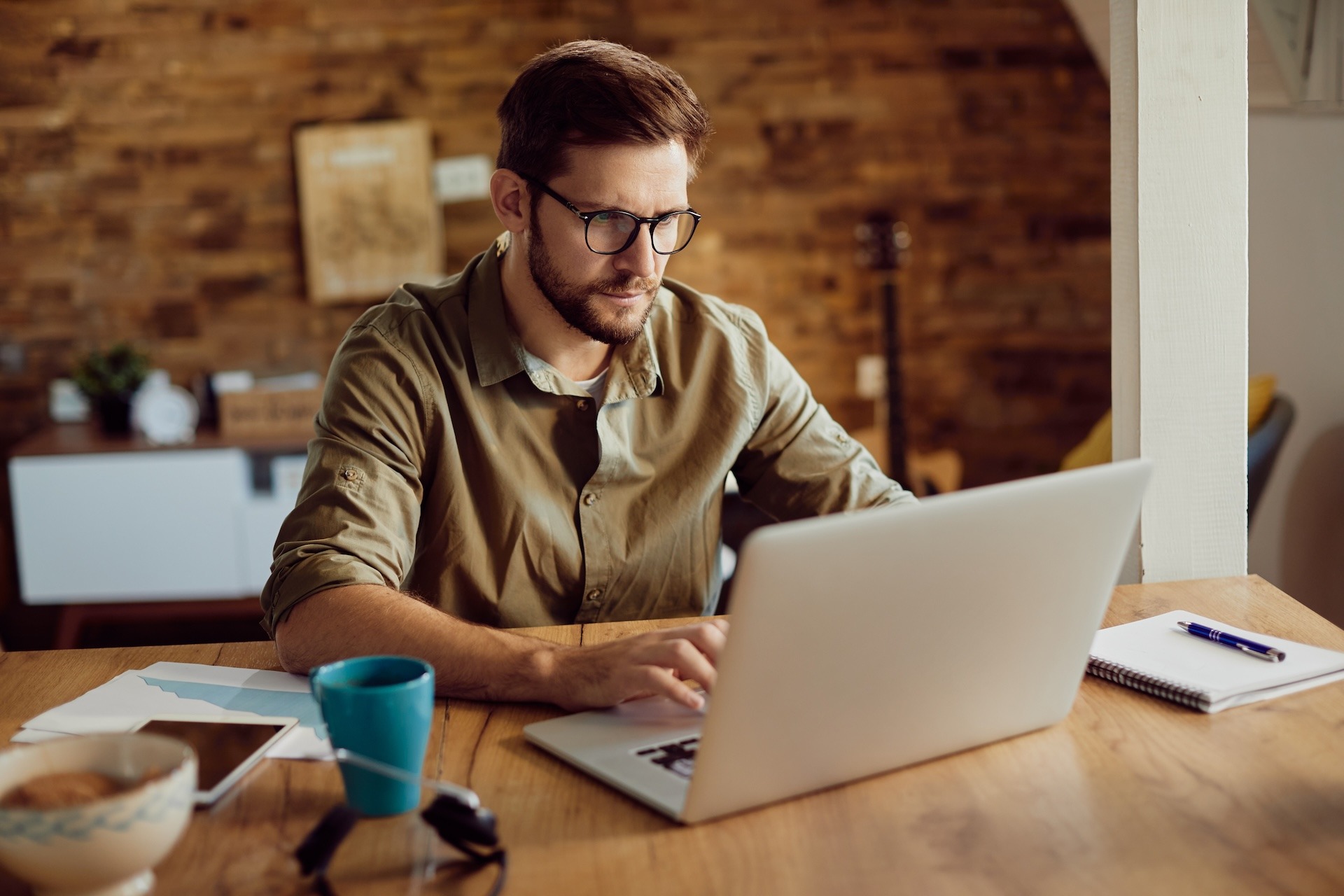 Male entrepreneur working on a computer at home. Freelance worker using laptop and typing an e-mail while working at home.