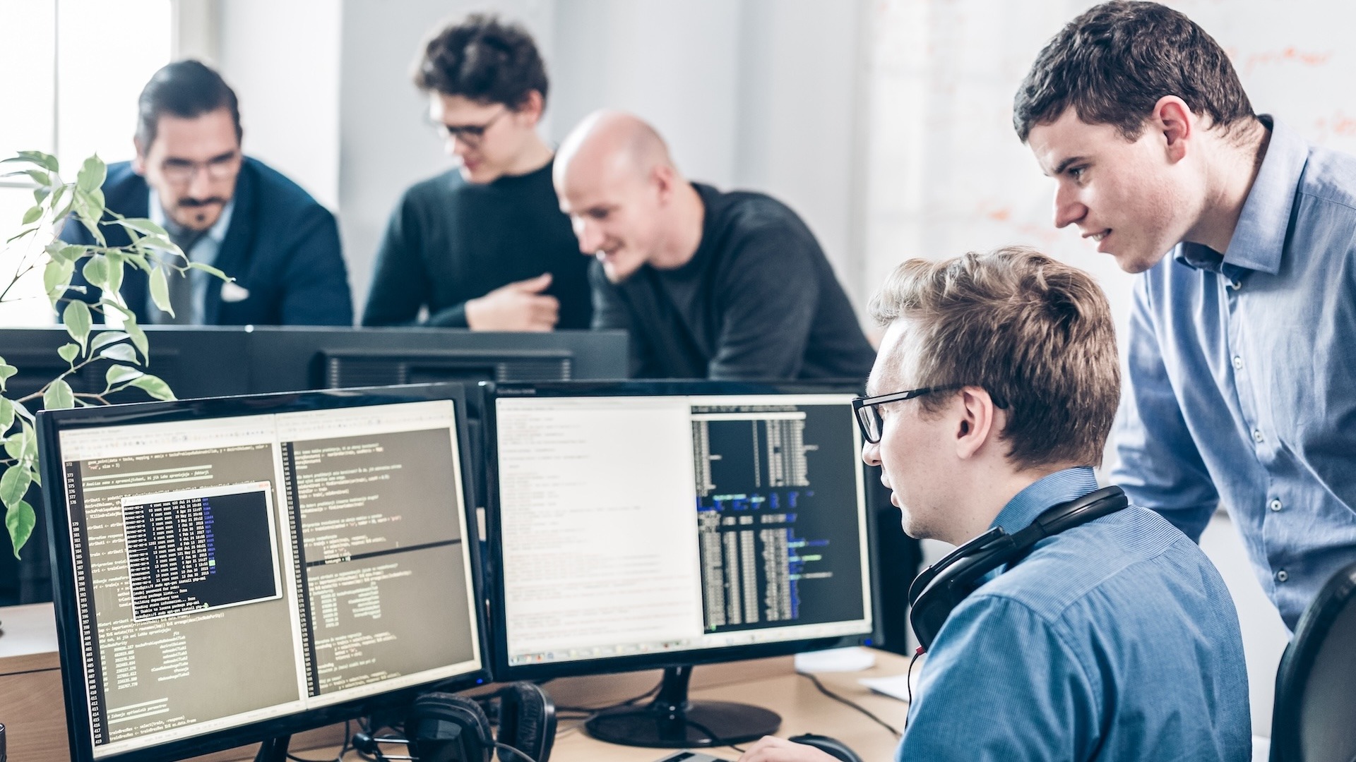 Startup business and entrepreneurship problem solving. Young AI programmers and IT software developers team brainstorming and programming on desktop computer in startup company share office space.